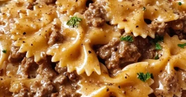 Creamy beef pasta dish garnished with herbs, served in a bowl.