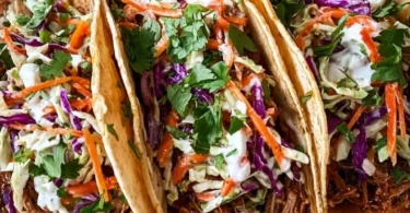 Delicious pulled pork tacos topped with tangy slaw on a wooden table