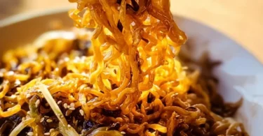 Stir-fried garlic ramen noodles served in a bowl garnished with green onions